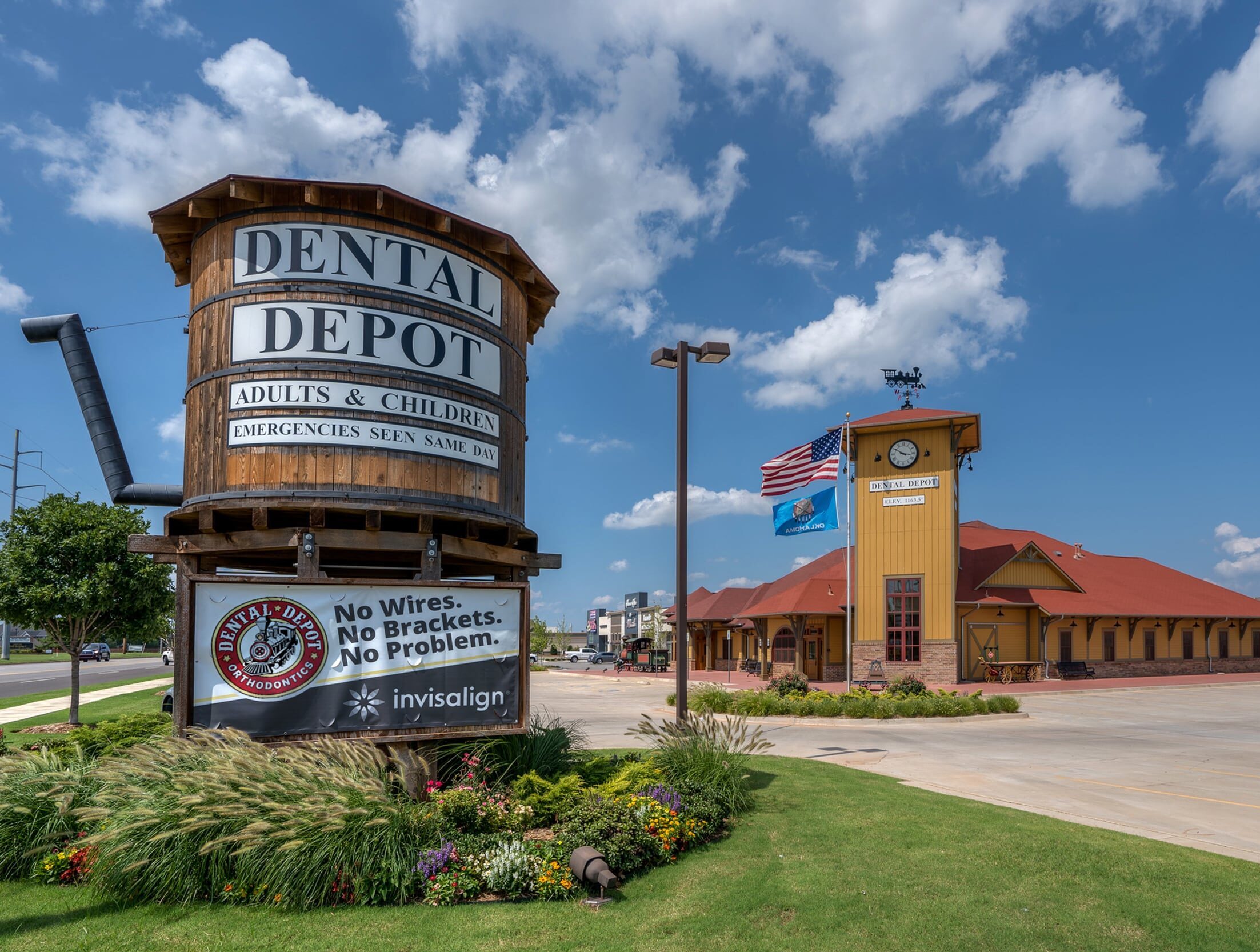 Exterior image of the Dental Depot dental clinic in North OKC with a clock tower in the foreground, yellow exterior, clock tower, and red roof.