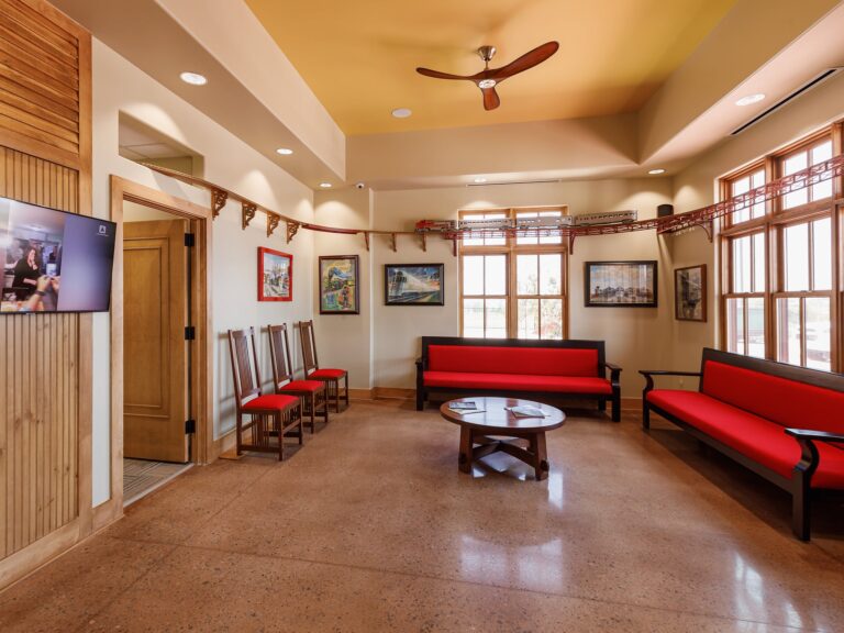 Reception area and waiting room at Dental Depot's Northwest OKC office with red furniture, light colored wood accents, and a model train track.