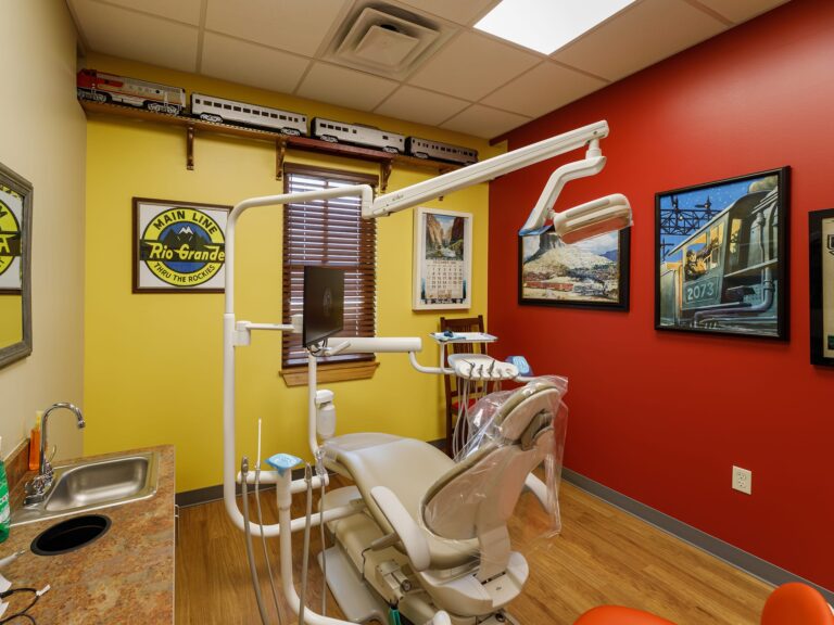 Dental operatory at Dental Depot's Northwest OKC dental clinic with red and yellow walls and train themed pictures on the walls.