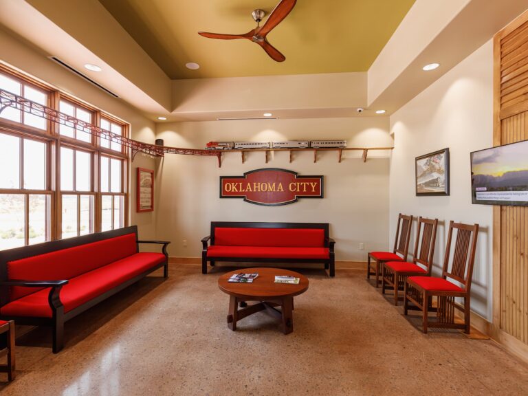 Reception area and waiting room at Dental Depot's Northwest OKC office with red furniture, light colored wood accents, and a model train track.