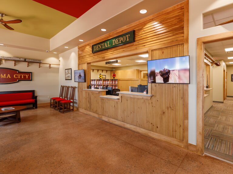 Reception area at Dental Depot's Northwest OKC office with red furniture, light colored wood accents, and a model train track.