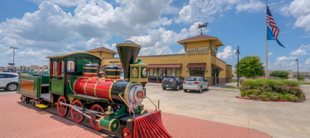 Exterior image of the Dental Depot dental office in Moore, OK with a train in the foreground.
