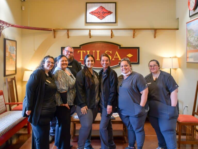 The Central Tulsa dental team poses in the reception area with big smiles