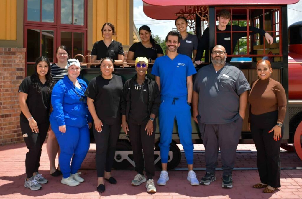 The Dental Depot dental team in Del City pose outside by the model train.