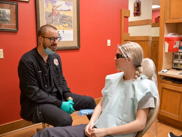 Dentist Dr. Tyler Duffy talks to a patient about her dental care at the South OKC dental clinic