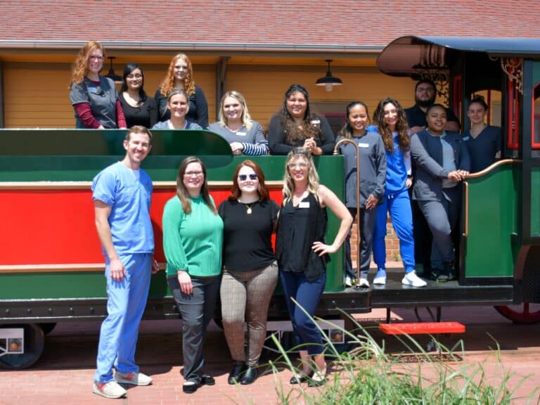 The Yukon dental team poses in from of the model train at Dental Depot's Yukon dental office