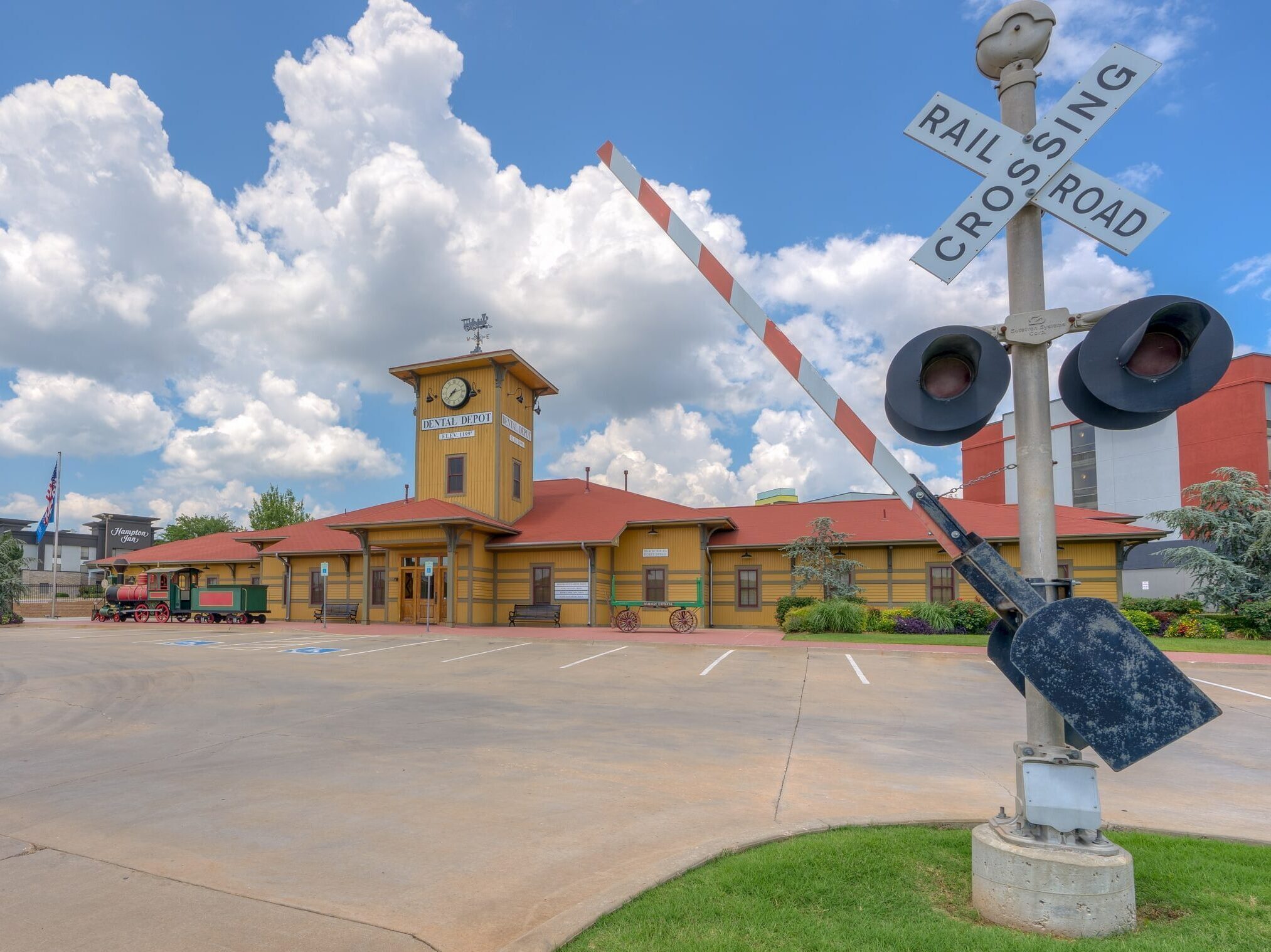 Exterior image of Dental Depot's dentist office in Midwest City, OK with a train track guard, yellow exterior, and red roof.