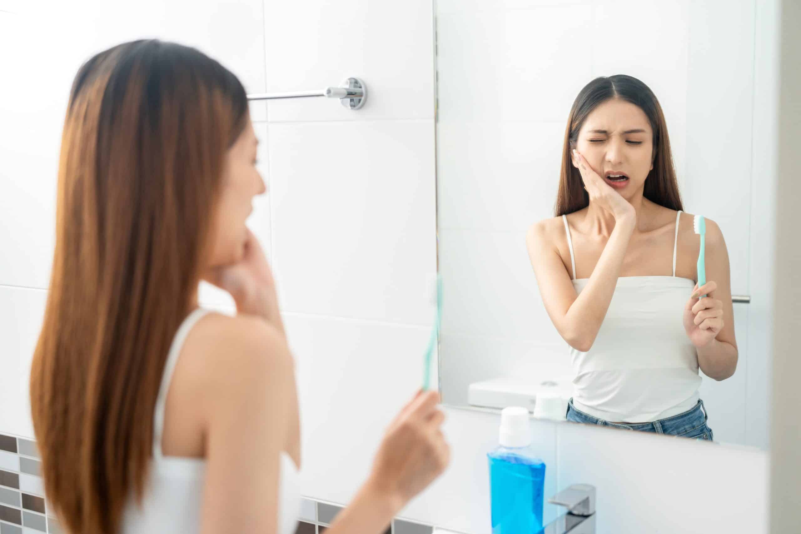 Asian woman puts her hand on her mouth and feels toothache because of tooth decay.