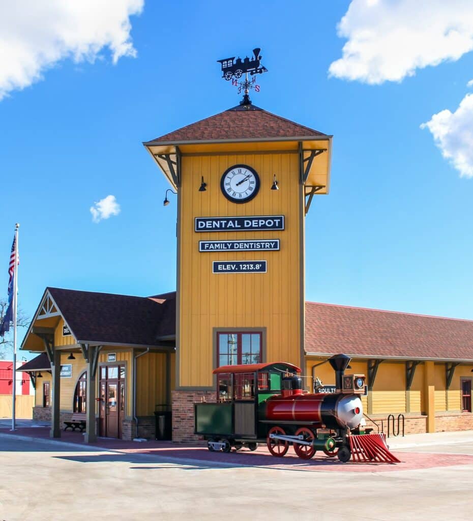 Exterior photo of Dental Depot's dentist office in Del CIty with a yellow exterior and a model train in front.