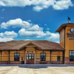 Dental Depot's Garnett Rd. Dental Clinic in Tulsa with a sunny blue sky in the background, a clock tower, and yellow walls.