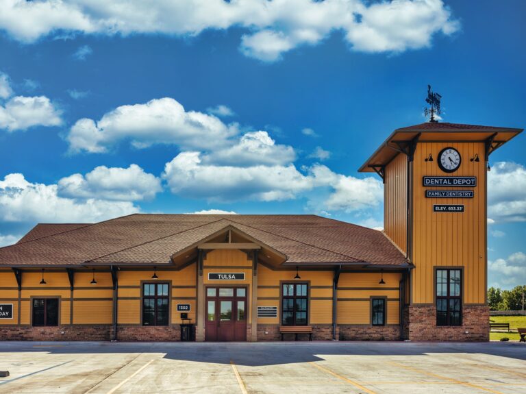 Dental Depot's Garnett Rd. Dental Clinic in Tulsa with a sunny blue sky in the background, a clock tower, and yellow walls.