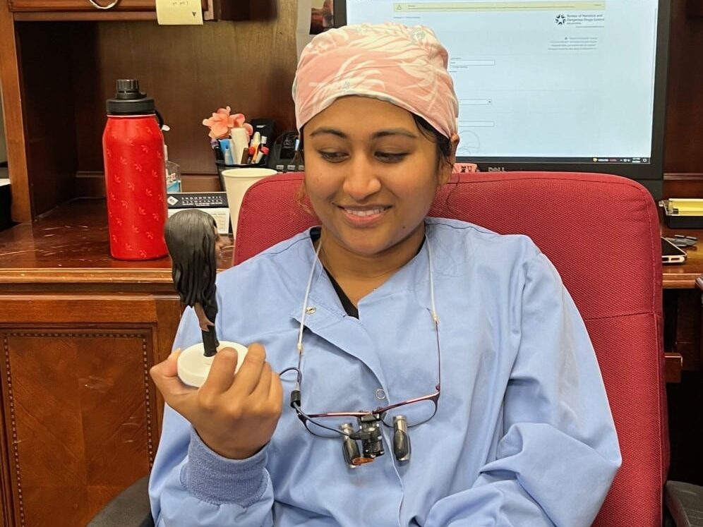 Dr. Ashnu Raju, Dental Depot's dentist in Midwest City, holds a bobblehead of herself.