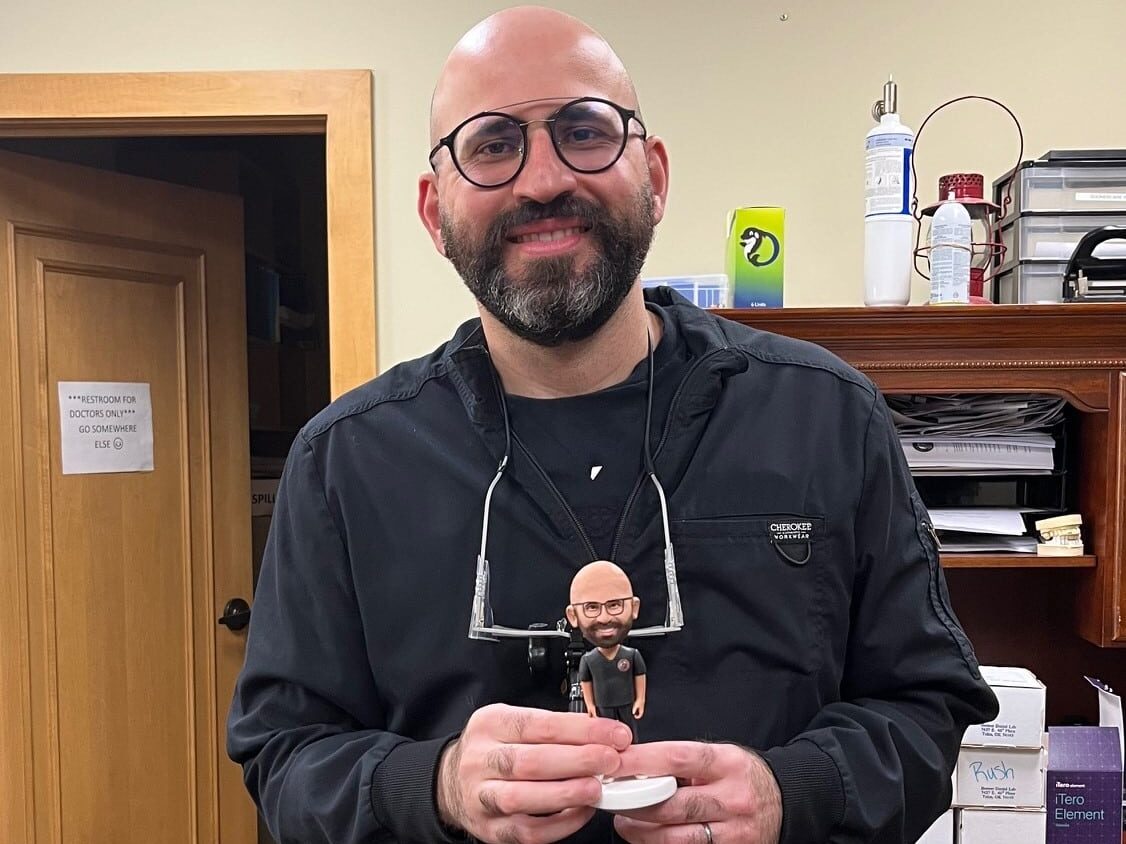 Dr. Zahir Kouzbari, Dental Depot's dentist in Midwest City, holds a bobblehead of himself.