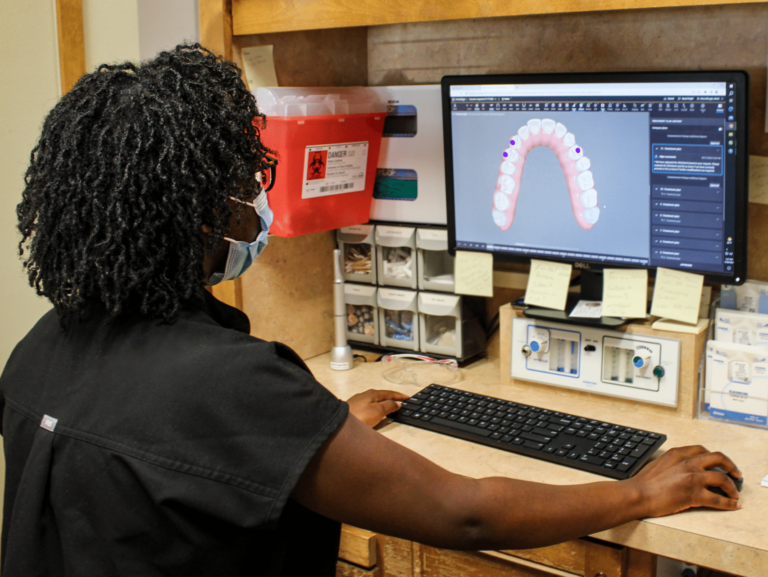 A dentist looks at an upper jaw scan on a computer monitor.