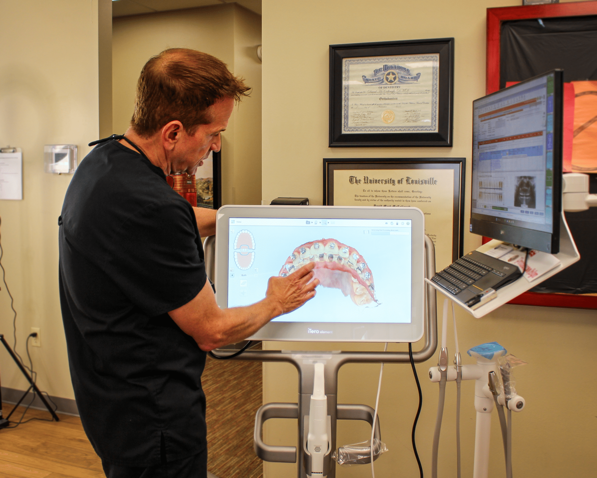 An orthodontist shows a scan of a mouth on a screen for Invisalign treatment