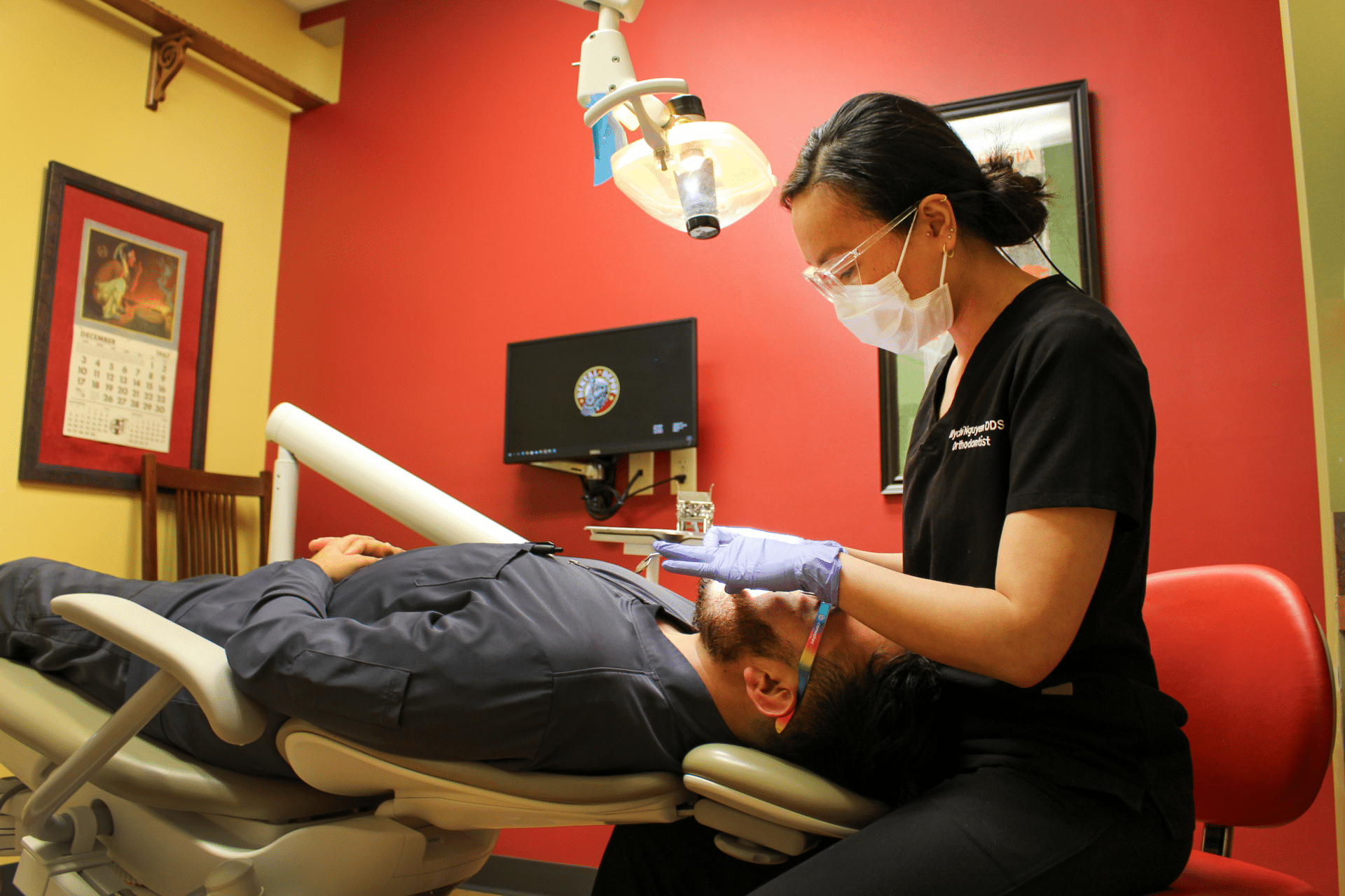 Dentist is working on a dental patient while they lay in the dental chair.