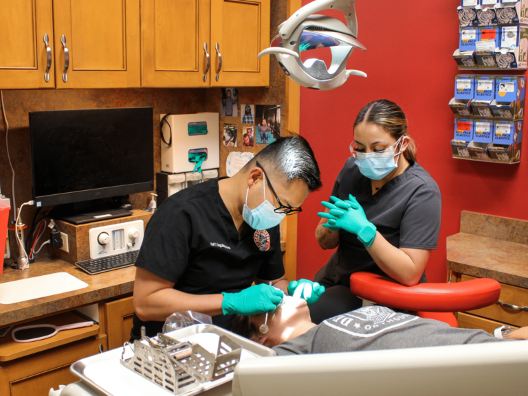 Dental Depot dentists examine a patient in a red exam room.