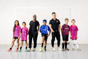 Kids wearing Invicto Futsal jerseys sponsored by Dental Depot stand next to dentists and pose in their gear.