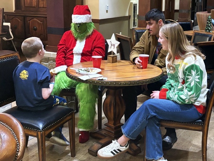 A person dressed as The Grinch entertains a child at a community event.