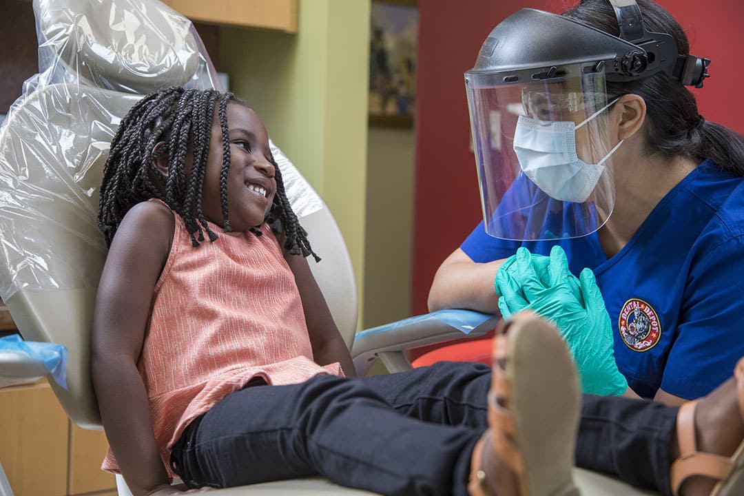 A small black child talks with a dental hygienist at dental depot