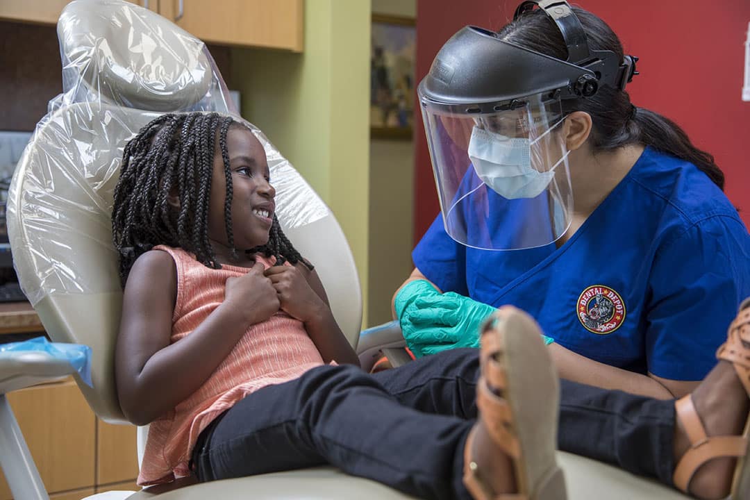 A small black child talks with a dental hygienist at dental depot