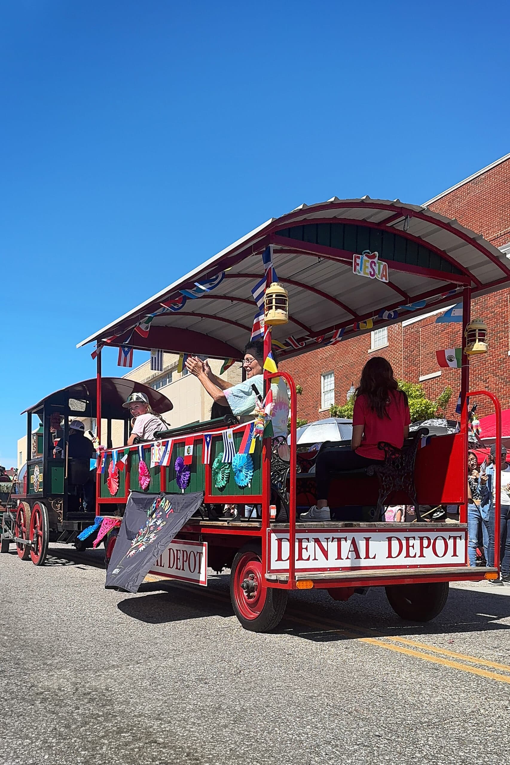Dental Depot's parade train car rolls through a parade on a sunny day.