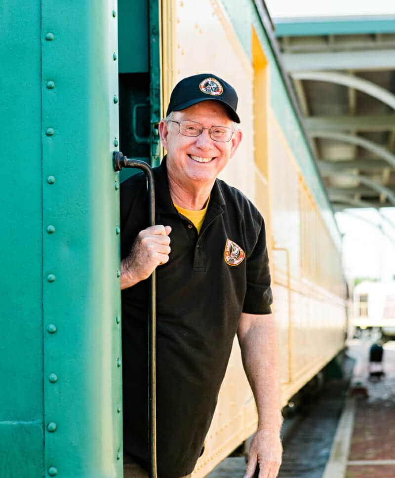 Dr. Glenn standing at the door of a train at a train station