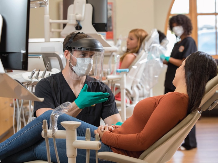 A dentist works with a patient in the dental chair.