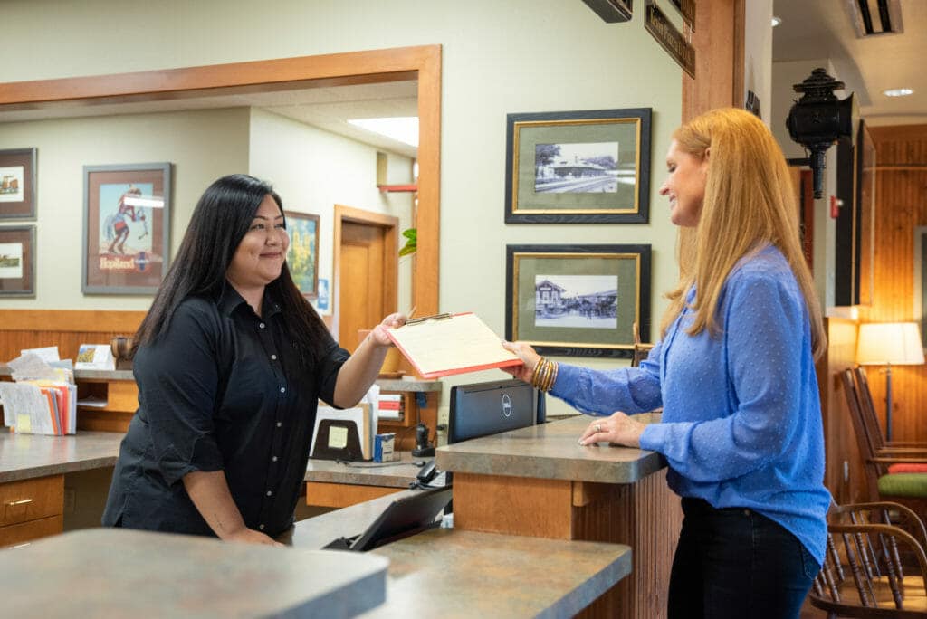 front desk employee handing a patient paperwork