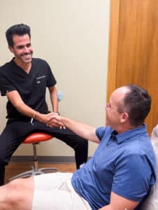 An orthodontist from Dental Depot in Oklahoma shakes the hand of an enthusiastic patient.