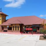 West Norman Dental Clinic Exterior with yellow walls, a clock tower, and a model train.