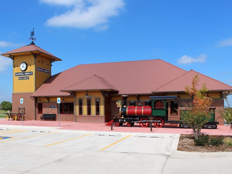 West Norman Dental Clinic Exterior with yellow walls, a clock tower, and a model train.