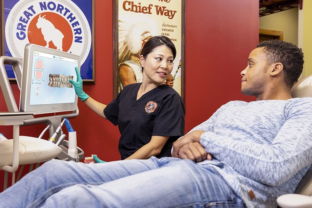 A dentist covers a dental treatment plan with a patient in a dentist office.