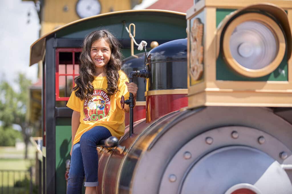 A young girl smiles sitting on the train at dental depot.